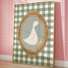 a duck with a bow on its head is in a gold frame against a pink wall