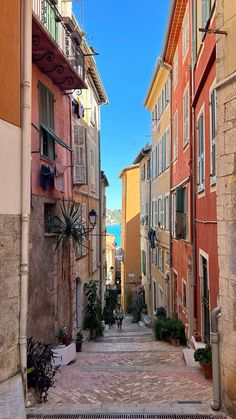 an alley way with buildings and plants on either side