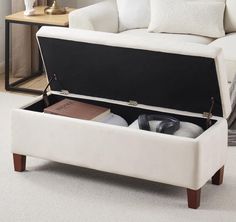 a white couch sitting next to a coffee table with a book and other items in it