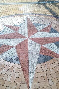 a red and white star is in the middle of a brick floored area with a bench