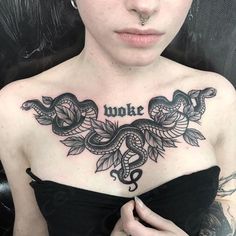 a woman with a snake tattoo on her chest and the words woke written in cursive writing