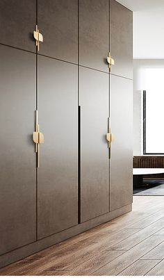 an empty room with wooden flooring and large gray cabinets in front of a window