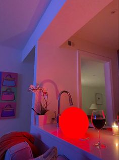 a red light shines on the counter top next to a wine glass and candle