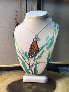 a necklace with a butterfly hanging from it's back on a mannequin