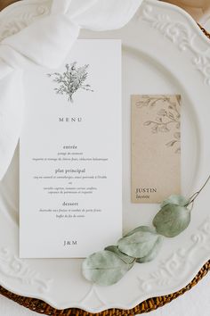 a white plate topped with a menu and green leaves