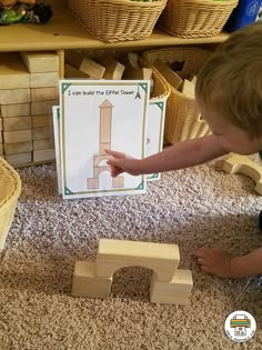 a young boy playing with wooden blocks in front of a sign that says i can build the tower