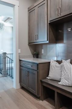 a wooden bench sitting in the middle of a kitchen next to a doorway with a chandelier above it