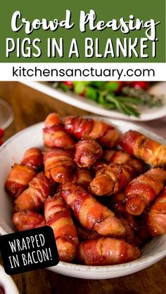 a bowl filled with pigs in a blanket sitting on top of a table next to other plates