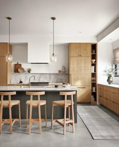 a kitchen with an island and bar stools in front of the countertop area