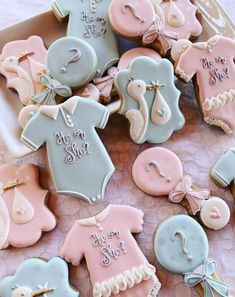 baby shower cookies are in a box on a table with pink and blue onesuits