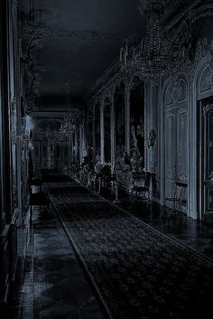 an empty hallway with chandeliers and chairs in the dark, black - and - white photo