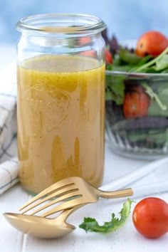 a jar filled with dressing next to a salad