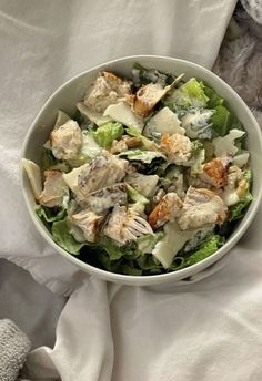 a white bowl filled with salad on top of a bed