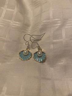 This beautiful pair of Seashell charm earrings is the perfect addition to your earrings collection. It features a beautiful shade of blue  on the inner part of the seashell with a white pearl in the center of the seashell. The charms are enamel. The closure of the earrings are hypo-allergenic hooks. This can be personalized, and you may request a non pierced closure in silver or gold. If you would like to see what this would look like before purchasing, please send me a message. Lavender Mist, Fish Hook Earrings, Fairy Dust, Earrings Collection, Charm Earrings, Earings Piercings, Earring Gifts, Pearl White, Shades Of Blue