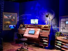 a desk with a laptop on top of it in a room filled with books and other items