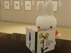 a stuffed rabbit reading a book on top of a table