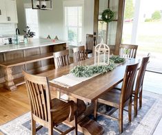 a dining room table and chairs in front of an open kitchen area with sliding glass doors