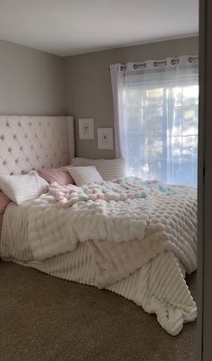 a large bed sitting in the middle of a bedroom next to a window with curtains