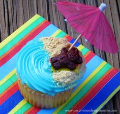 a cupcake with blue icing and toppings on top, sitting next to an umbrella