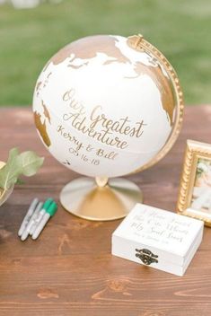 a table topped with a globe and two small boxes filled with flowers on top of it