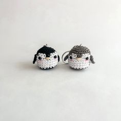 two small crocheted keychains are sitting next to each other on a white surface