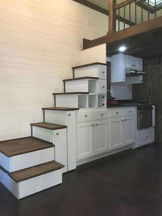 a kitchen with white cabinets and wooden stairs