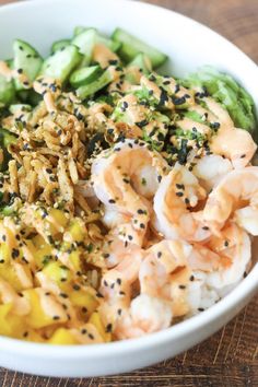 a white bowl filled with shrimp, broccoli and other vegetables on top of a wooden table