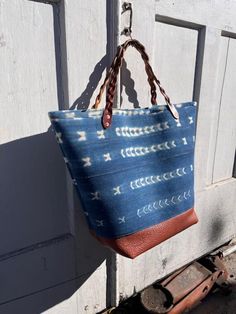 The Thalia Tote is an oversized fun time. This giant tote will give you extra joy every time you head out for an adventure. Made with vintage indigo dyed cotton fabric that is hand printed from Ghana, lined in ticking stripe, buffalo leather at the bottom, sturdy Latigo braided handles, and copper rivets. The lining has three pockets sized for an i-phone, a water bottle, and a magazine. The bag itself can hold blankets, towels, pic-nic supplies or anything you need to tote around for a fun day out. Hidden interior details: The indigo fabric is fused to an extra thick padded interlining then faced with a cotton canvas giving the tote structure. There is a Latigo (thick saddle leather) footing sandwiched between the buffalo leather and lining.  The fabric is vintage and hand printed which me Pic Nic, Indigo Fabric, Vintage Indigo, The Buffalo, Saddle Leather, Ticking Stripe, Indigo Dye, Buffalo Leather, I Phone