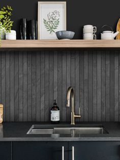 a kitchen counter with a sink and some pots on it next to a wooden shelf