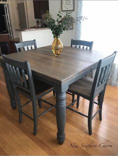 a dining room table with four chairs and a vase on top of it in front of a window