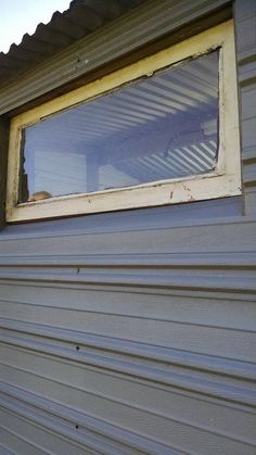 a window on the side of a house that is missing some shingles and needs to be replaced