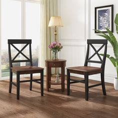 two wooden chairs sitting next to each other on top of a hard wood floor in front of a window