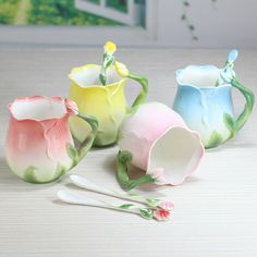 four different colored vases with spoons next to each other