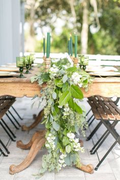 the table is set with greenery and candles for an outdoor dinner party or reception