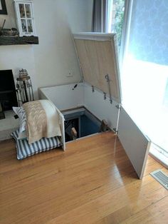 an open trunk sitting on top of a hard wood floor next to a window with curtains