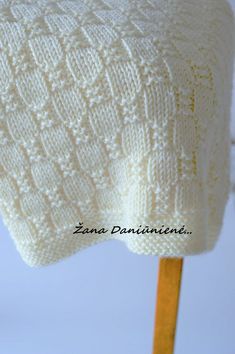 a white knitted sweater sitting on top of a wooden stick