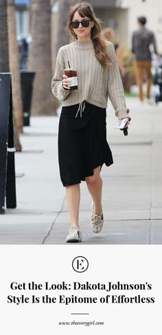 a woman walking down the street while holding a coffee