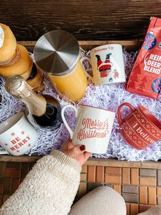 someone is holding two coffee mugs in front of some books and other items on the table