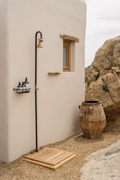 a white building with a wooden door and window next to a large potted plant