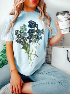 Boho Floral Tee COMFORT COLORS® Vintage Pressed Flowers Blue Wildflowers Dark Cottagecore Shirt Nature Lover Gift Botanical Gardening Shirt  Shop all The June Kind - https://www.etsy.com/ca/shop/TheJuneKind? * Unique Hand drawn Graphics * Women Owned Small Business * Made to Order, especially for You ---------- Please read before placing your order -------------- 1. This apparel is GENDER NEUTRAL / UNISEX. The relaxed fit is flattering for all bodies. 2. Refer SIZE CHART for measurements. Upsize Blue Floral Print Crew Neck Shirt, Blue Crew Neck Shirt With Floral Print, Blue Plants Print Short Sleeve T-shirt, Blue Plant Print Summer Top, Blue Plant Print Crew Neck Top, Blue Plant Print Top For Summer, Spring Blue Floral Print Shirt, Blue Floral Print Relaxed Fit Tops, Blue Floral Print Top With Relaxed Fit