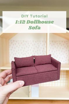 the dollhouse sofa is being held up by someone's hand in front of it