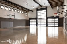 an empty basketball court with lights on the ceiling and doors open to let in light