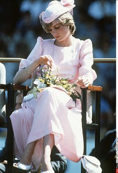 the princess is sitting in a chair and looking down at her flowery bouquet while wearing a pink dress