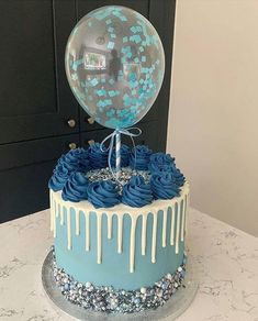 a cake with blue frosting and balloons on top is displayed in the instagramr