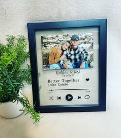 a couple is sitting together in front of a wall with an mp3 player and potted plant