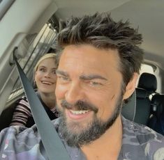 two women and a man in the back seat of a car smiling at the camera