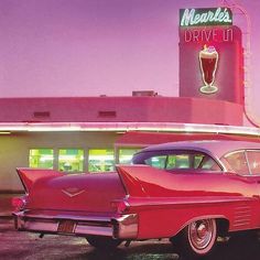 an old red car parked in front of a drive - in movie theater