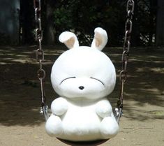 a white stuffed animal sitting on top of a swing