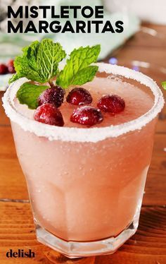 a pink drink with mint and cranberry garnish in a glass on a wooden table