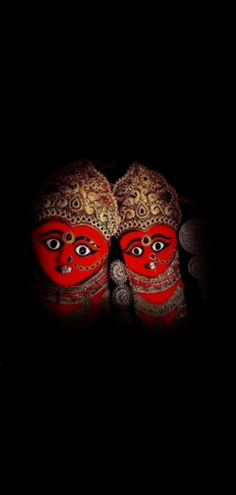 two red masks sitting on top of each other in the dark with their faces painted